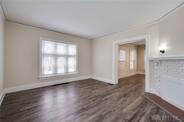 spare room featuring ornamental molding, visible vents, dark wood finished floors, and baseboards