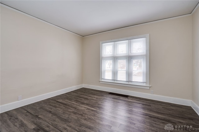 spare room with baseboards, visible vents, dark wood-type flooring, and ornamental molding