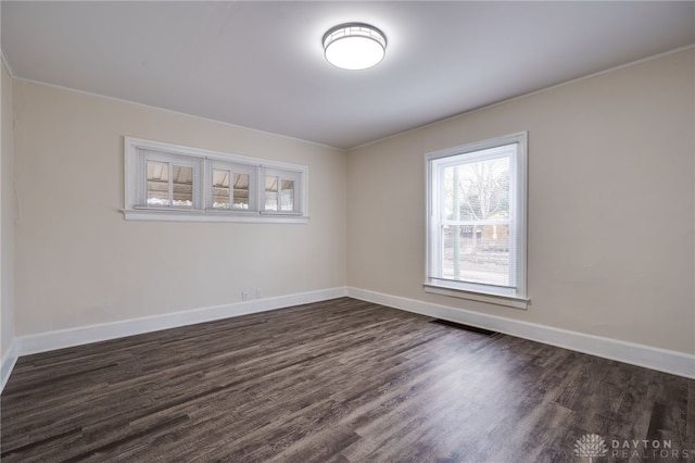 spare room with baseboards, visible vents, and dark wood-style flooring