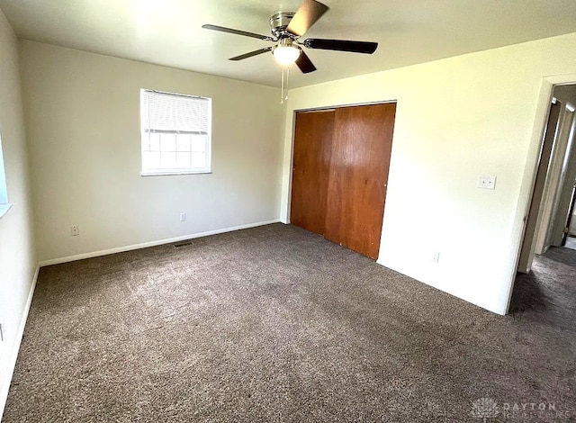 unfurnished bedroom with dark colored carpet, a closet, and ceiling fan