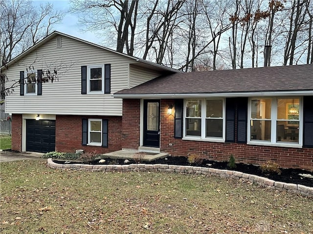 tri-level home with a garage, driveway, brick siding, and a shingled roof