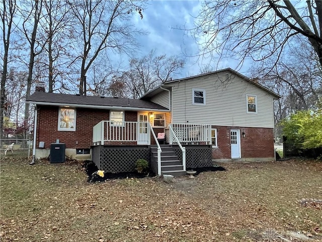 rear view of house featuring a wooden deck, a chimney, central AC unit, and brick siding