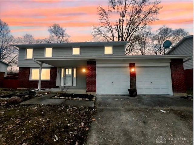 traditional-style home featuring an attached garage, driveway, a porch, and brick siding