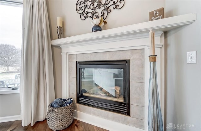 room details with a tile fireplace, baseboards, and wood finished floors