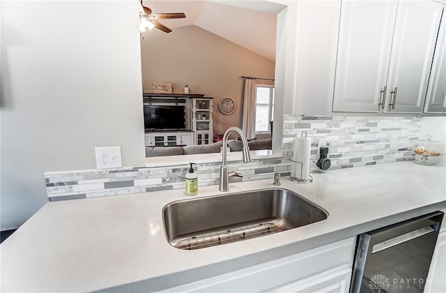 kitchen with dishwasher, light countertops, a sink, and lofted ceiling