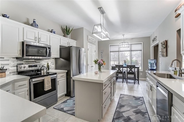 kitchen featuring a center island, stainless steel appliances, tasteful backsplash, light countertops, and a sink