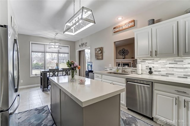 kitchen with light countertops, backsplash, appliances with stainless steel finishes, white cabinets, and a sink