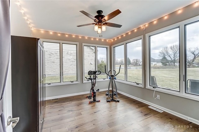 exercise area with visible vents, ceiling fan, baseboards, and wood finished floors