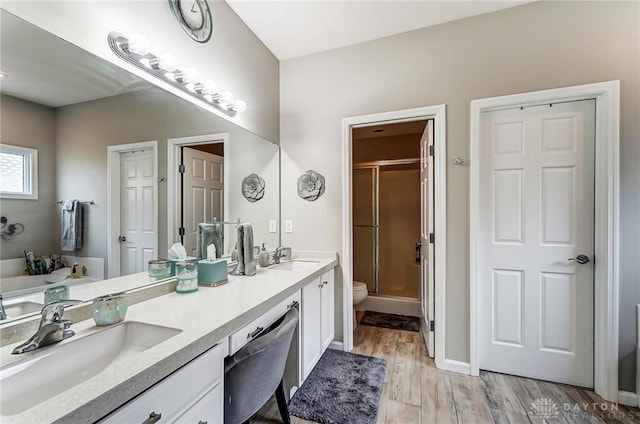 full bath featuring double vanity, wood finished floors, a stall shower, and a sink