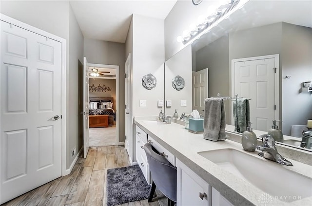 ensuite bathroom with double vanity, ensuite bath, a sink, and wood finished floors