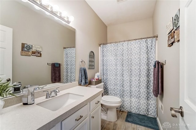 bathroom with toilet, a shower with shower curtain, wood finished floors, visible vents, and vanity