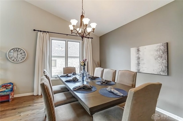 dining area featuring lofted ceiling, baseboards, light wood finished floors, and an inviting chandelier