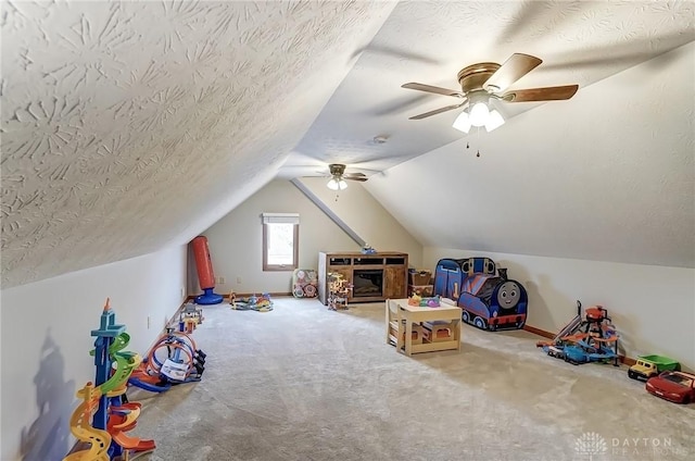 playroom featuring carpet, baseboards, vaulted ceiling, and a textured ceiling