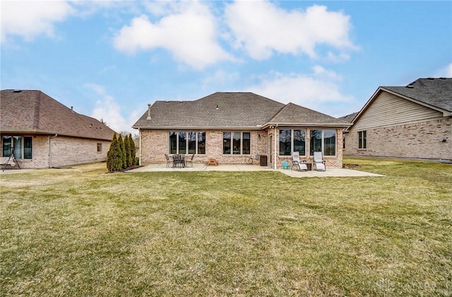 rear view of property featuring a yard, brick siding, and a patio