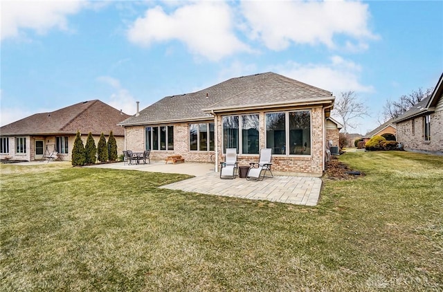 back of property with roof with shingles, a lawn, a patio, and brick siding