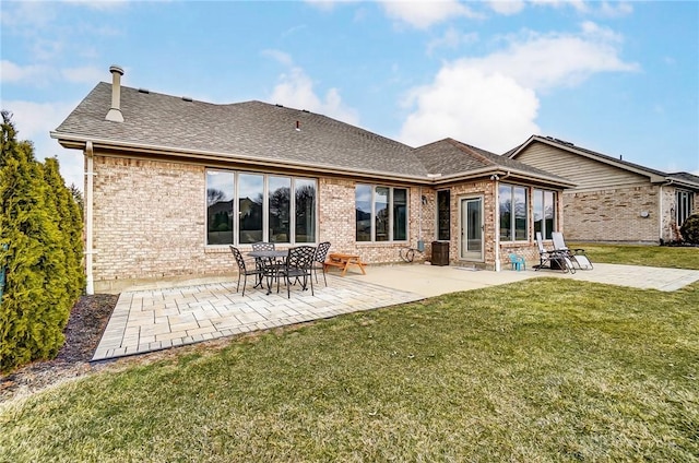 rear view of property featuring brick siding, a yard, a patio, and roof with shingles