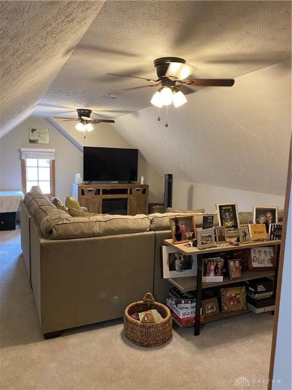 living room with lofted ceiling, ceiling fan, a textured ceiling, and carpet flooring