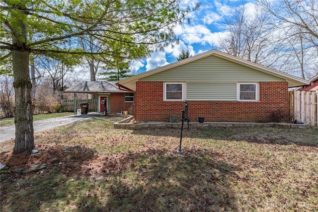 view of side of property with driveway, fence, a carport, and brick siding