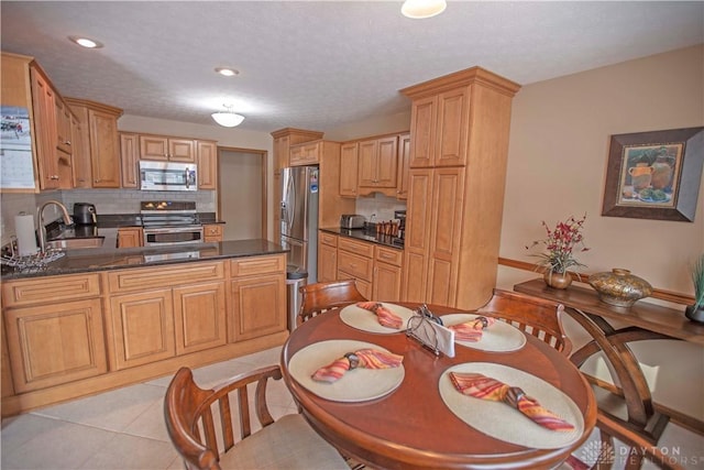 kitchen with decorative backsplash, appliances with stainless steel finishes, light tile patterned flooring, a sink, and a peninsula