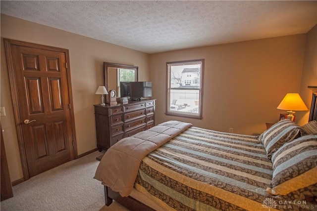 bedroom featuring light carpet, a textured ceiling, and baseboards