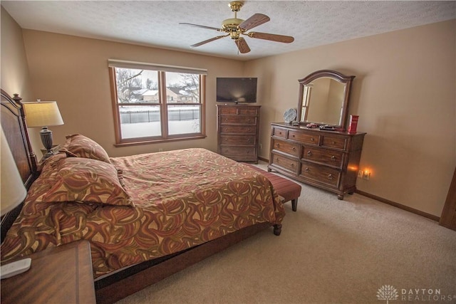 carpeted bedroom with a textured ceiling, a ceiling fan, and baseboards