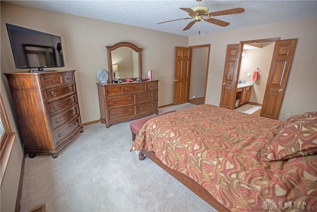 bedroom featuring light carpet, baseboards, a ceiling fan, and ensuite bathroom