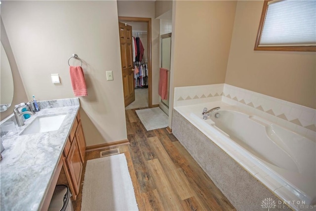 1250 Yankee Woods Dr, Washington Twp, OH 45458 - full bathroom featuring wood finished floors, vanity, a garden tub, a stall shower, and a walk in closet