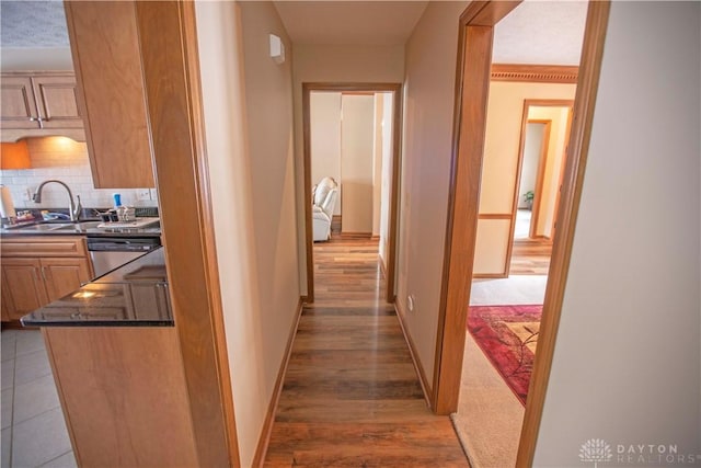 hall featuring light wood-style floors, a sink, and baseboards