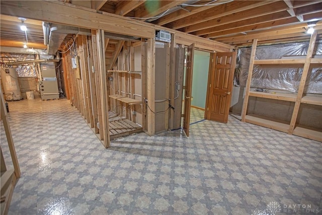 unfinished below grade area with water heater, tile patterned floors, visible vents, and heating unit