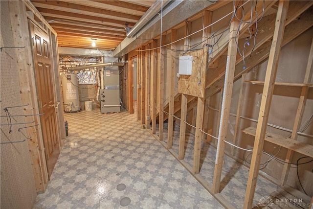 unfinished basement with gas water heater, heating unit, and tile patterned floors