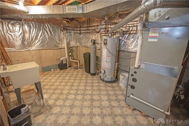 utilities featuring gas water heater, visible vents, and heating unit