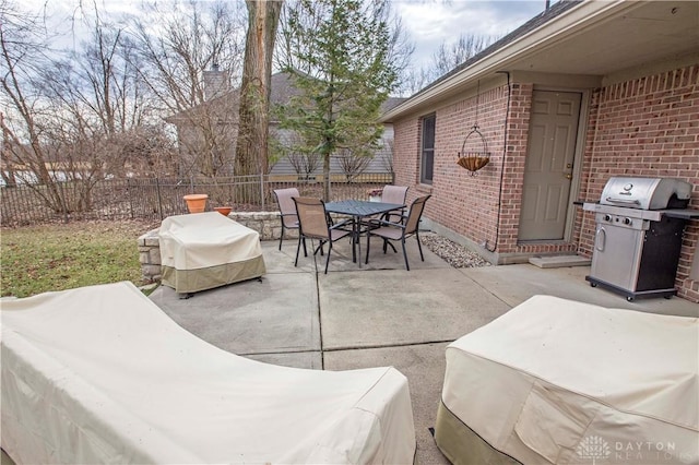 view of patio featuring a grill, fence, and outdoor dining space