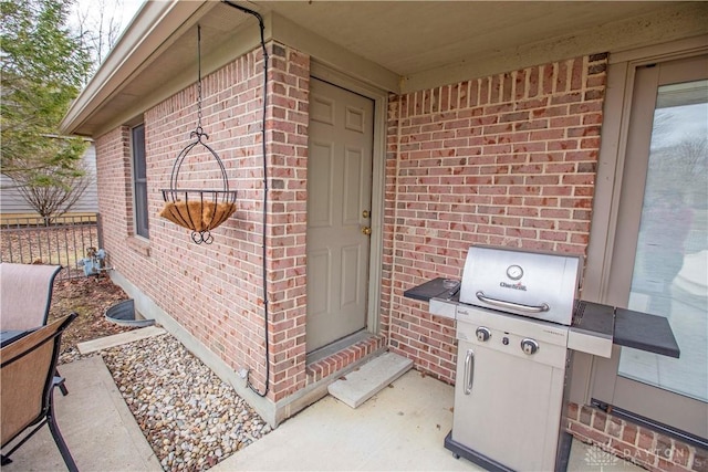 view of exterior entry with brick siding and fence