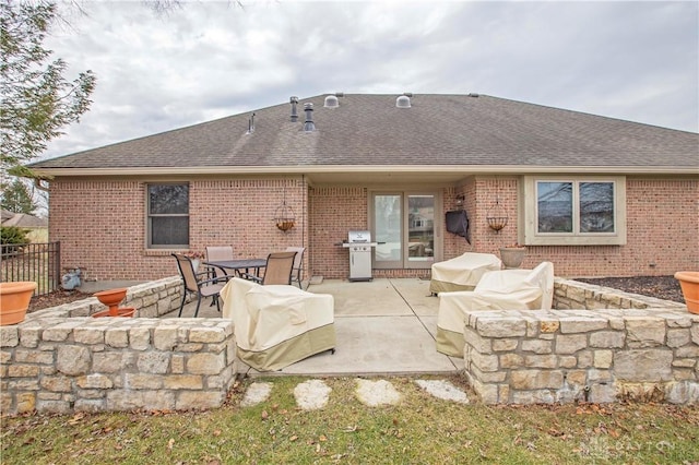 back of house featuring a patio, brick siding, a shingled roof, and fence