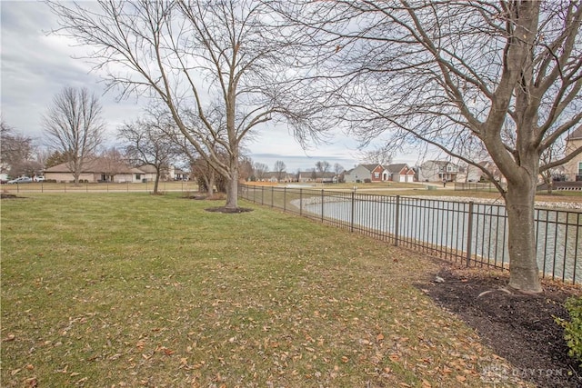 view of yard with a residential view, a water view, and fence