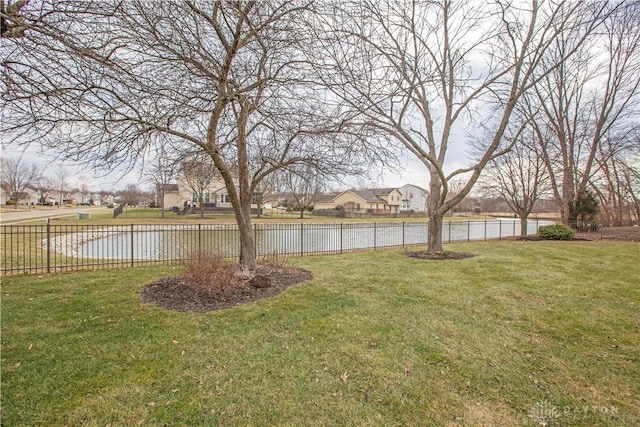 view of yard featuring a water view, fence, and a residential view