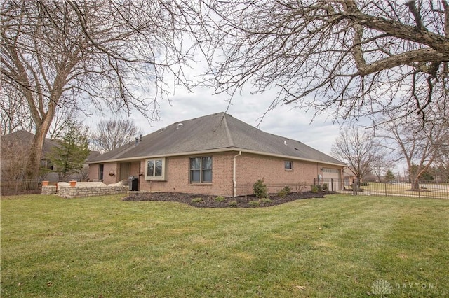 view of side of property with a garage, a yard, brick siding, and fence