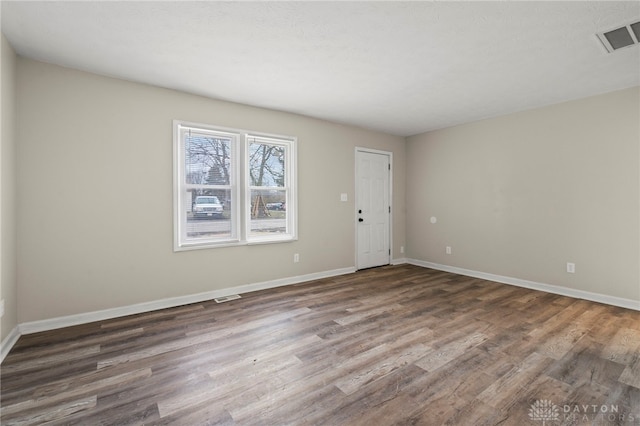 unfurnished room featuring baseboards, visible vents, and wood finished floors