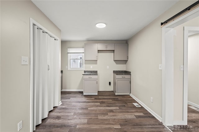 kitchen with baseboards, a barn door, dark wood-style flooring, and gray cabinetry