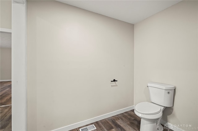 bathroom featuring toilet, wood finished floors, visible vents, and baseboards