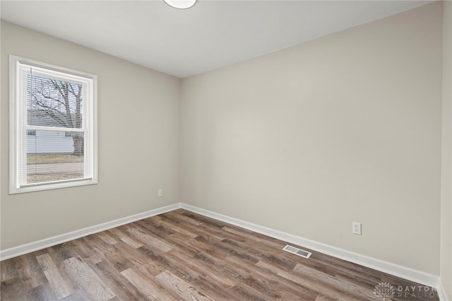 unfurnished room featuring wood finished floors, visible vents, and baseboards