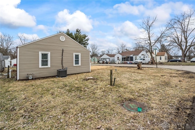 view of property exterior featuring a residential view, central AC, and a yard