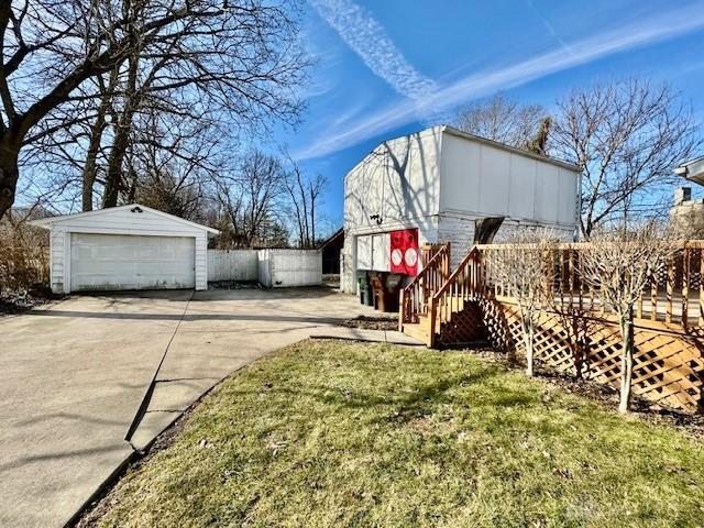 view of yard with a garage, an outbuilding, and a deck