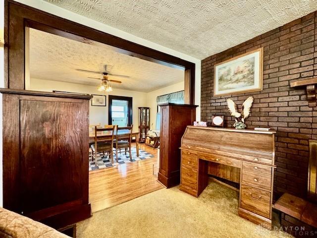 interior space featuring a ceiling fan, light carpet, and a textured ceiling