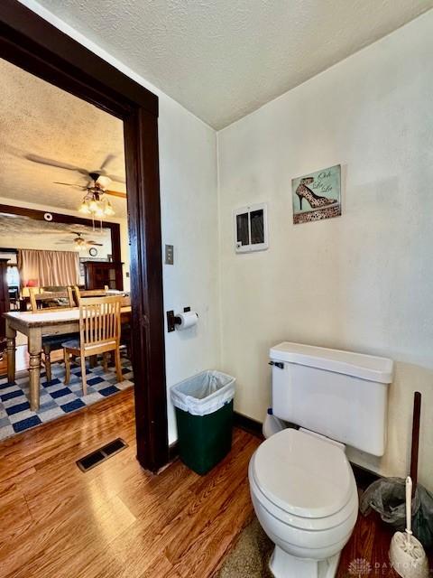 bathroom with visible vents, toilet, ceiling fan, a textured ceiling, and wood finished floors