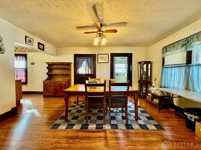 dining room featuring baseboards, plenty of natural light, a ceiling fan, and wood finished floors