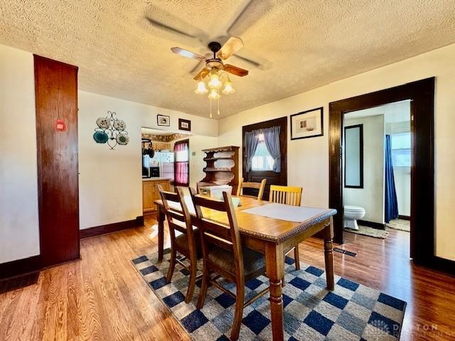 dining area with a ceiling fan, a textured ceiling, baseboards, and wood finished floors