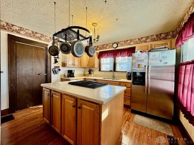 kitchen featuring a textured ceiling, dark wood finished floors, stainless steel refrigerator with ice dispenser, and a sink