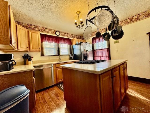 kitchen featuring light countertops, appliances with stainless steel finishes, a sink, and dark wood finished floors