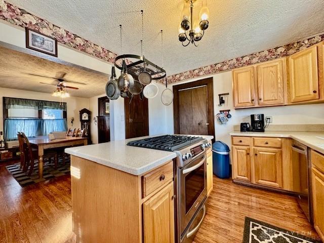 kitchen with stainless steel appliances, light countertops, light wood-style floors, a kitchen island, and a textured ceiling